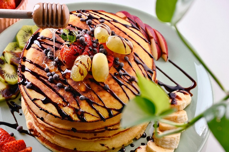 close-up of pancakes with fruit and chocolate syrup